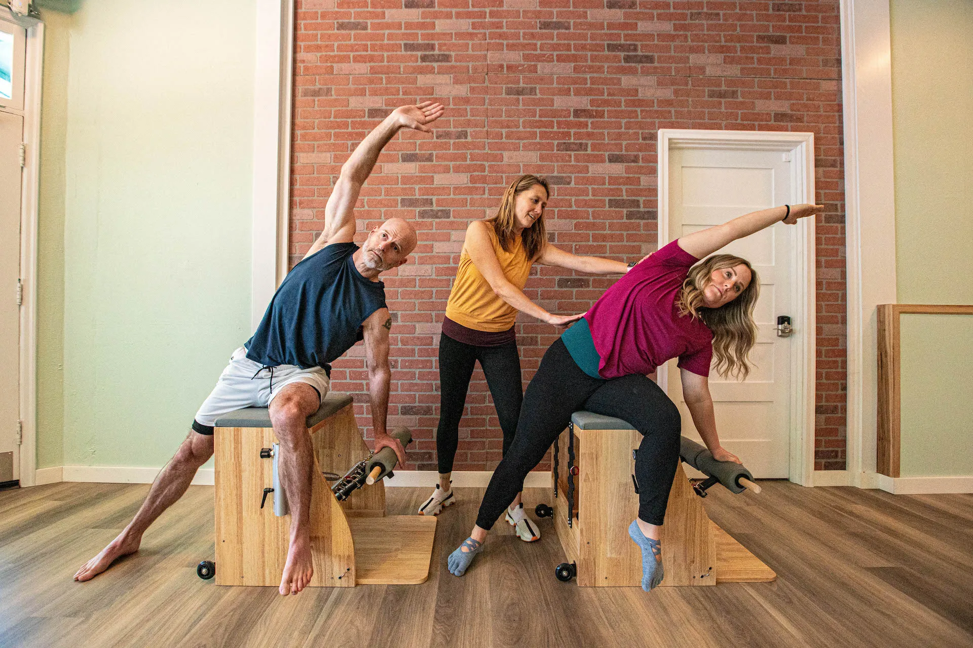 Reniera guiding two students through Pilates chair exercises at Trillium Pilates Studio
